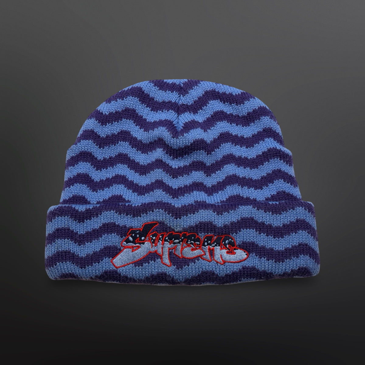 Supreme strikhue med lyseblåt og lilla bølgemønster, ombuk og broderet logo