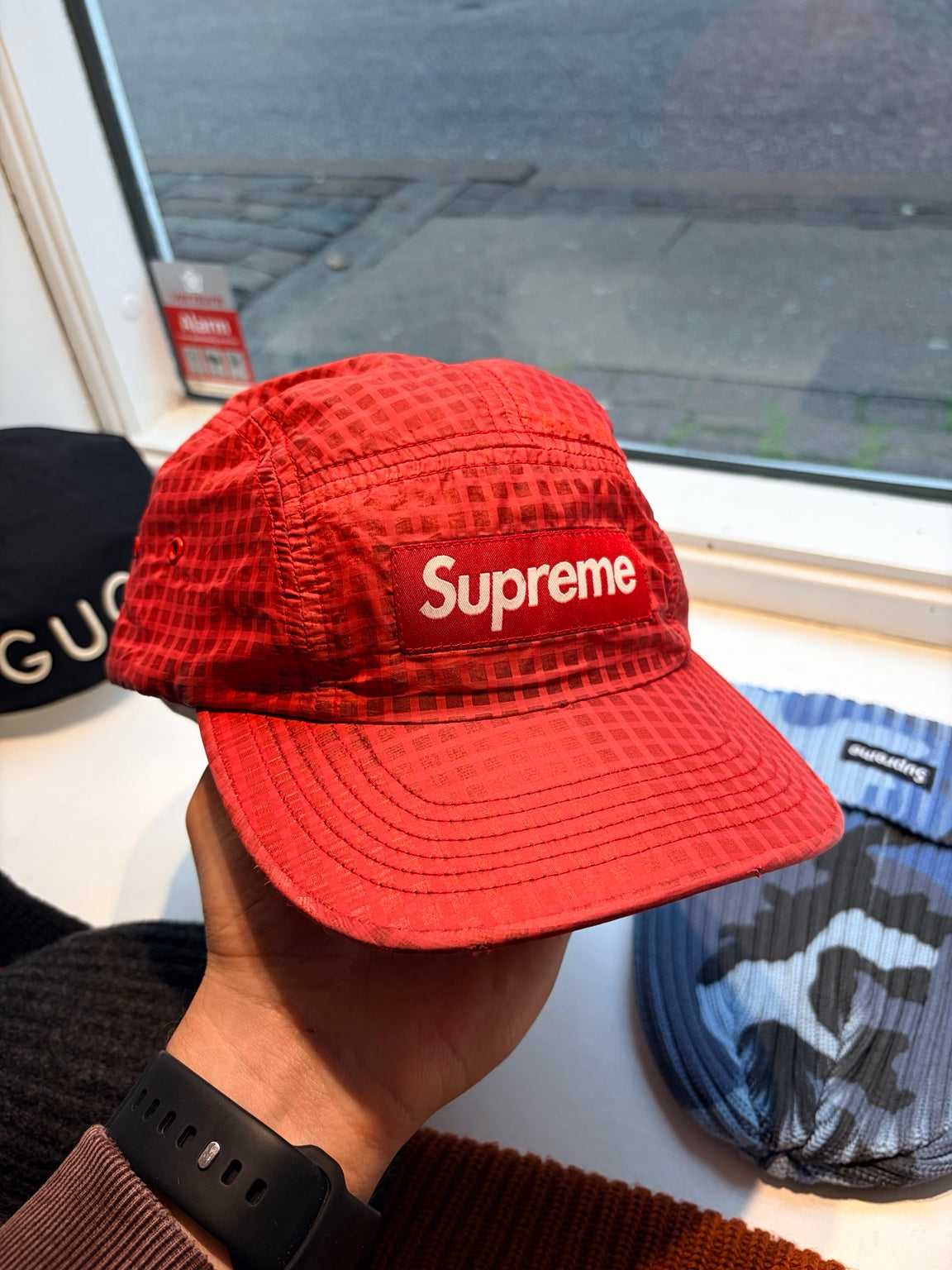 Originalfoto af rød Supreme-cap med tonalt gittermønster og lyst Supreme-logo