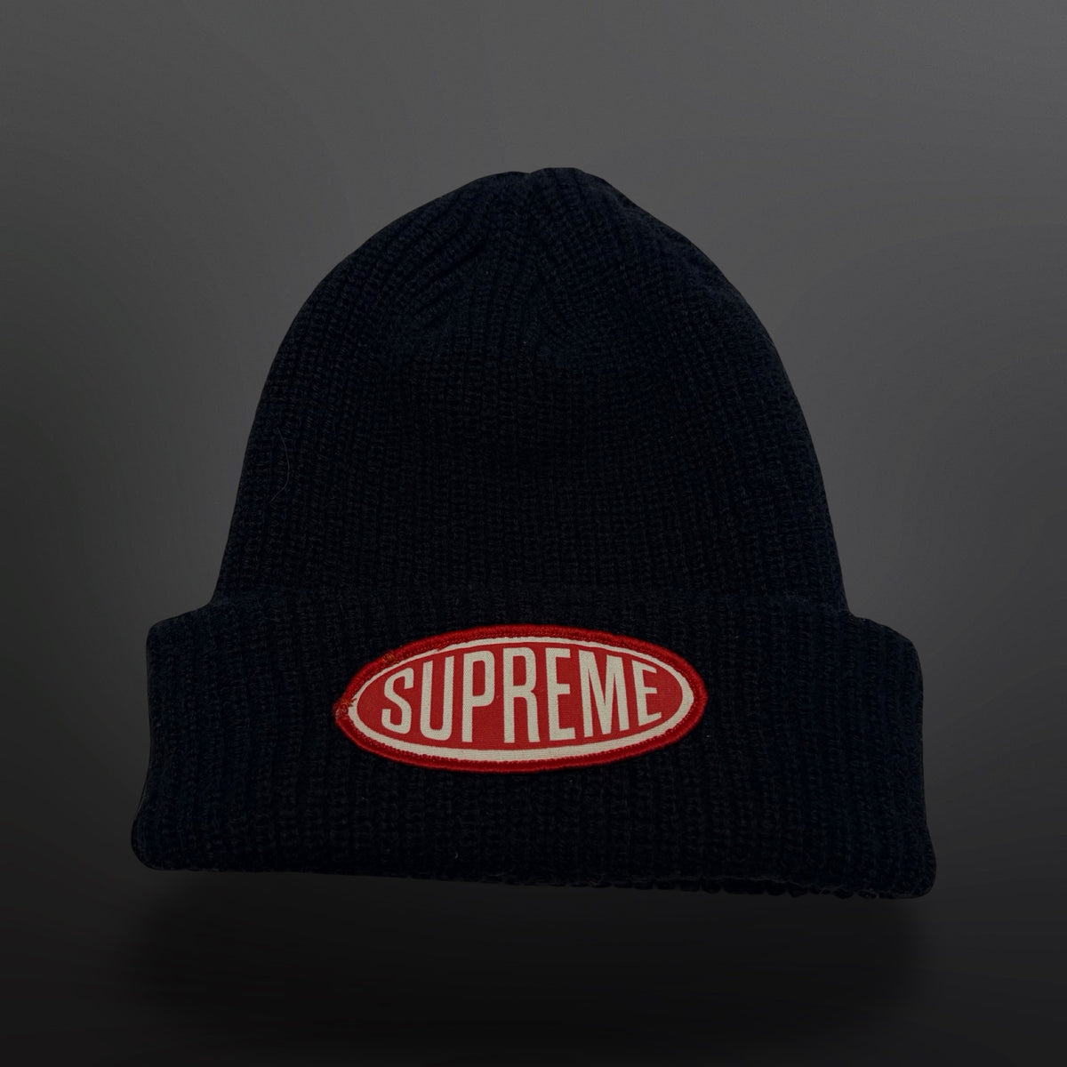 Sort ribstrikket Supreme-hue med bredt ombuk og oval rød og hvid Supreme-logopatch