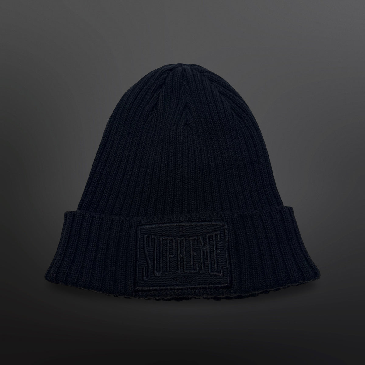 Sort Supreme-hue i ribstrik med bredt ombuk og stor sort logopatch på fronten