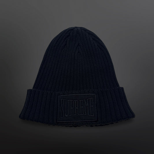 Sort Supreme-hue i ribstrik med bredt ombuk og stor sort logopatch på fronten