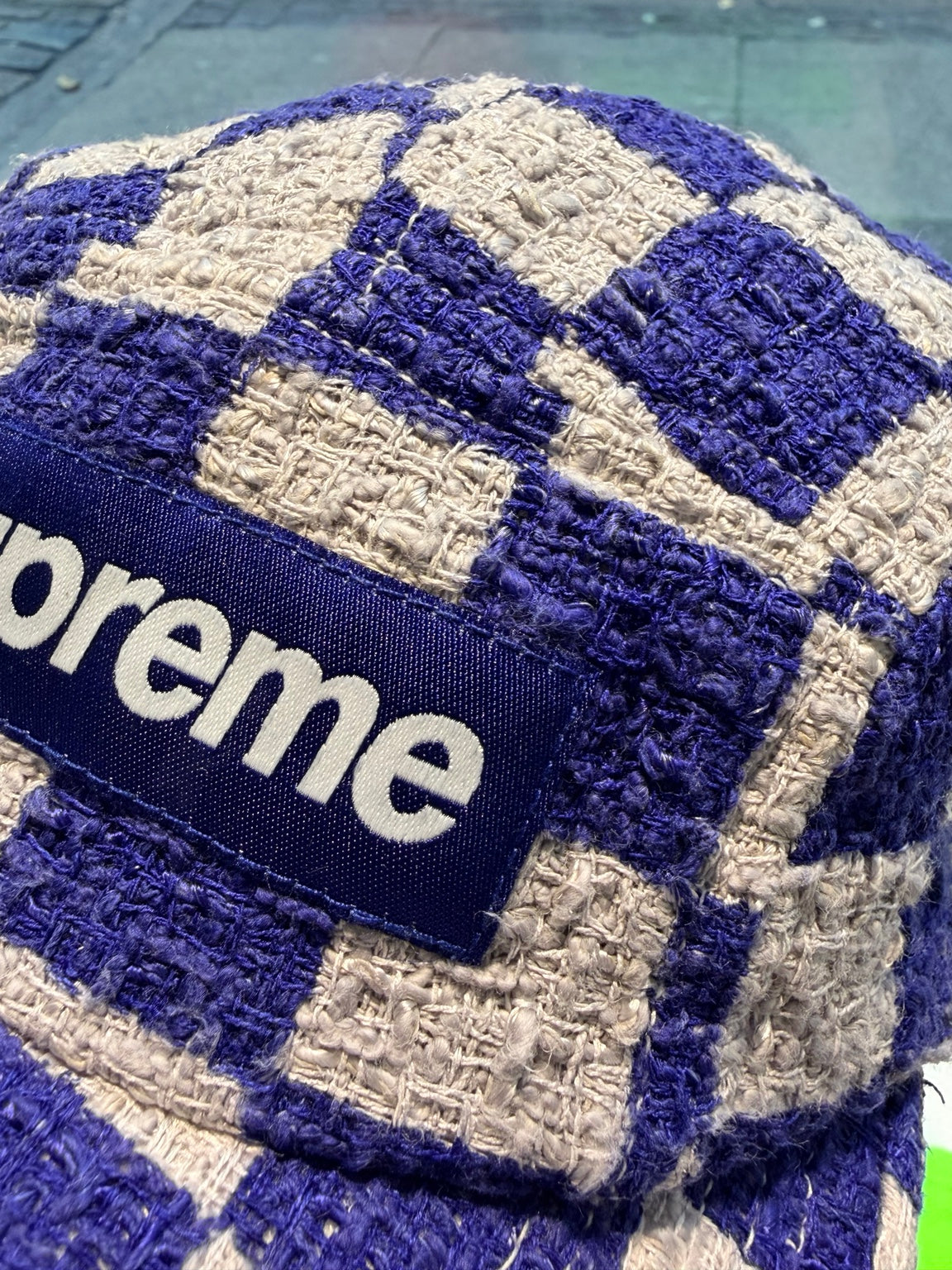Nærbillede af grovvævet ternet stof og Supreme-logomærke
